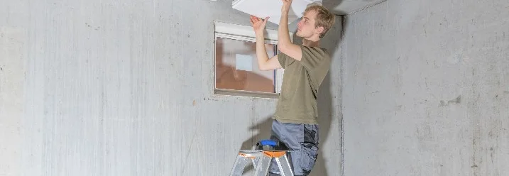 Person auf Leiter bringt Deckenplatten an